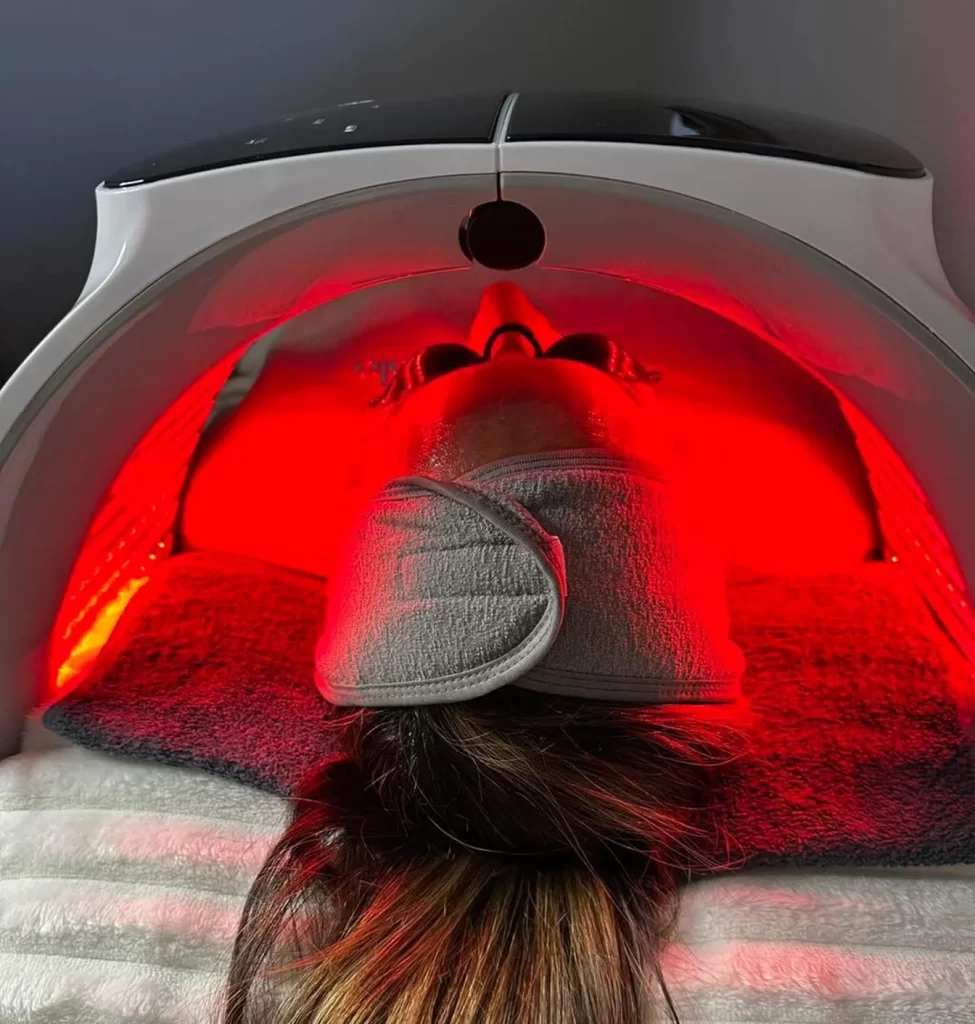 Client under a red LED light therapy panel during a Circadia facial