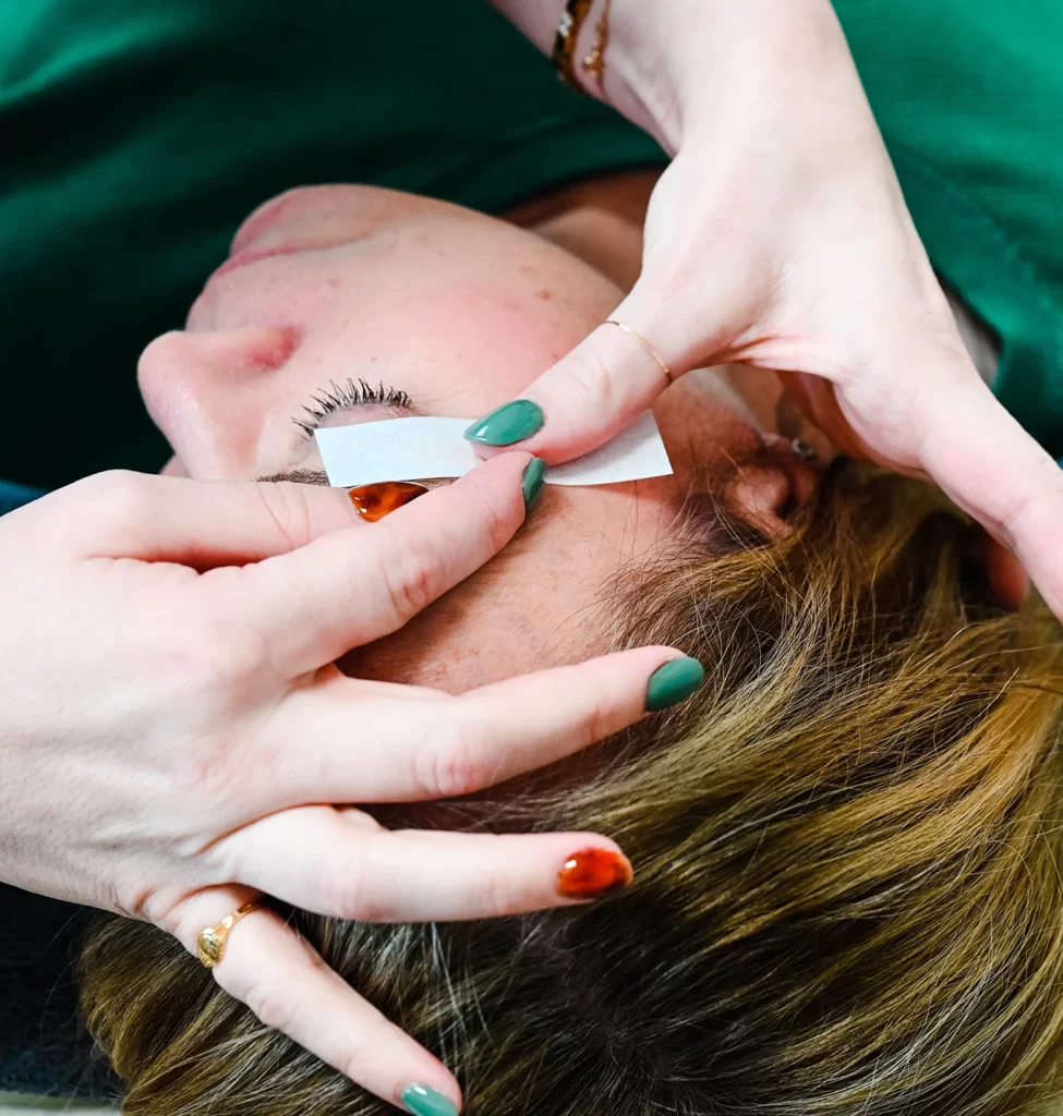 Esthetician waxing a client's eyebrows