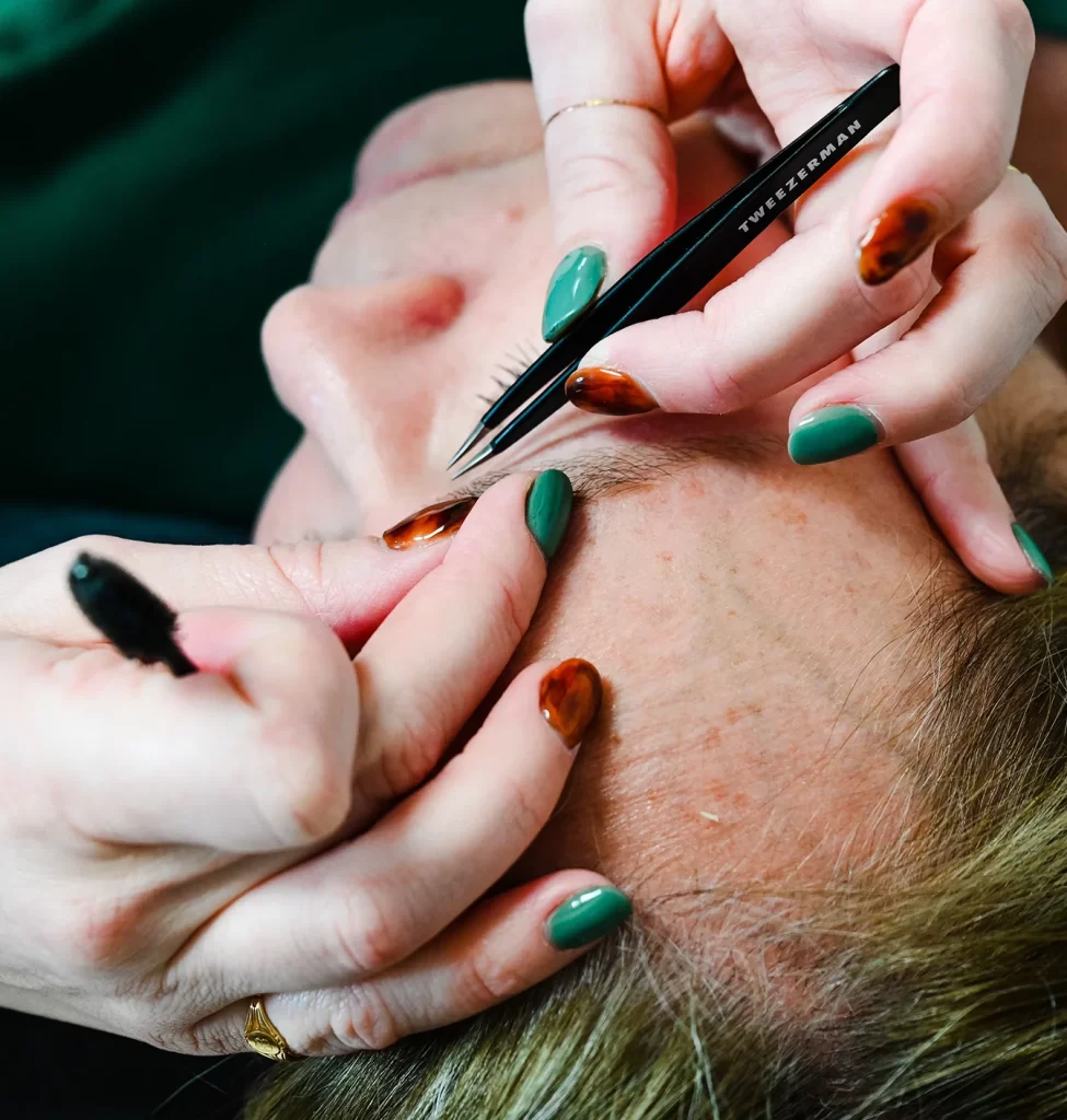Esthetician shaping a client's eyebrows