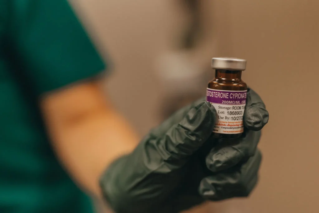 Gloved hand holding a vial of testosterone cypionate