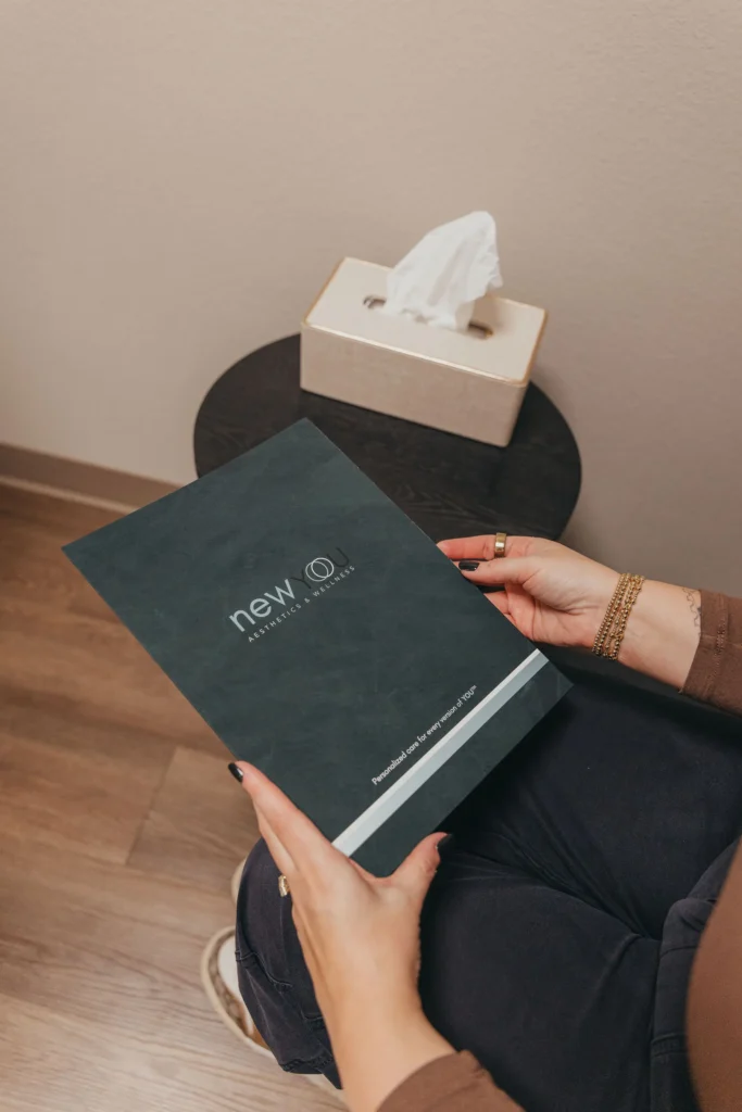 Client holding a New You Aesthetics & Wellness consultation folder